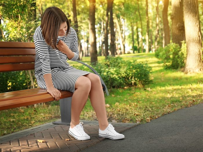 Woman on bench outside holding chest