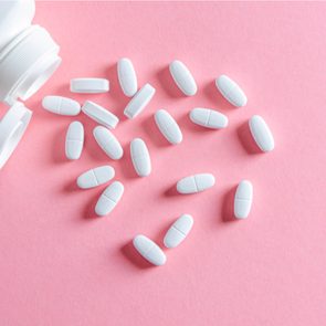 A white container containing placebos against a pink background