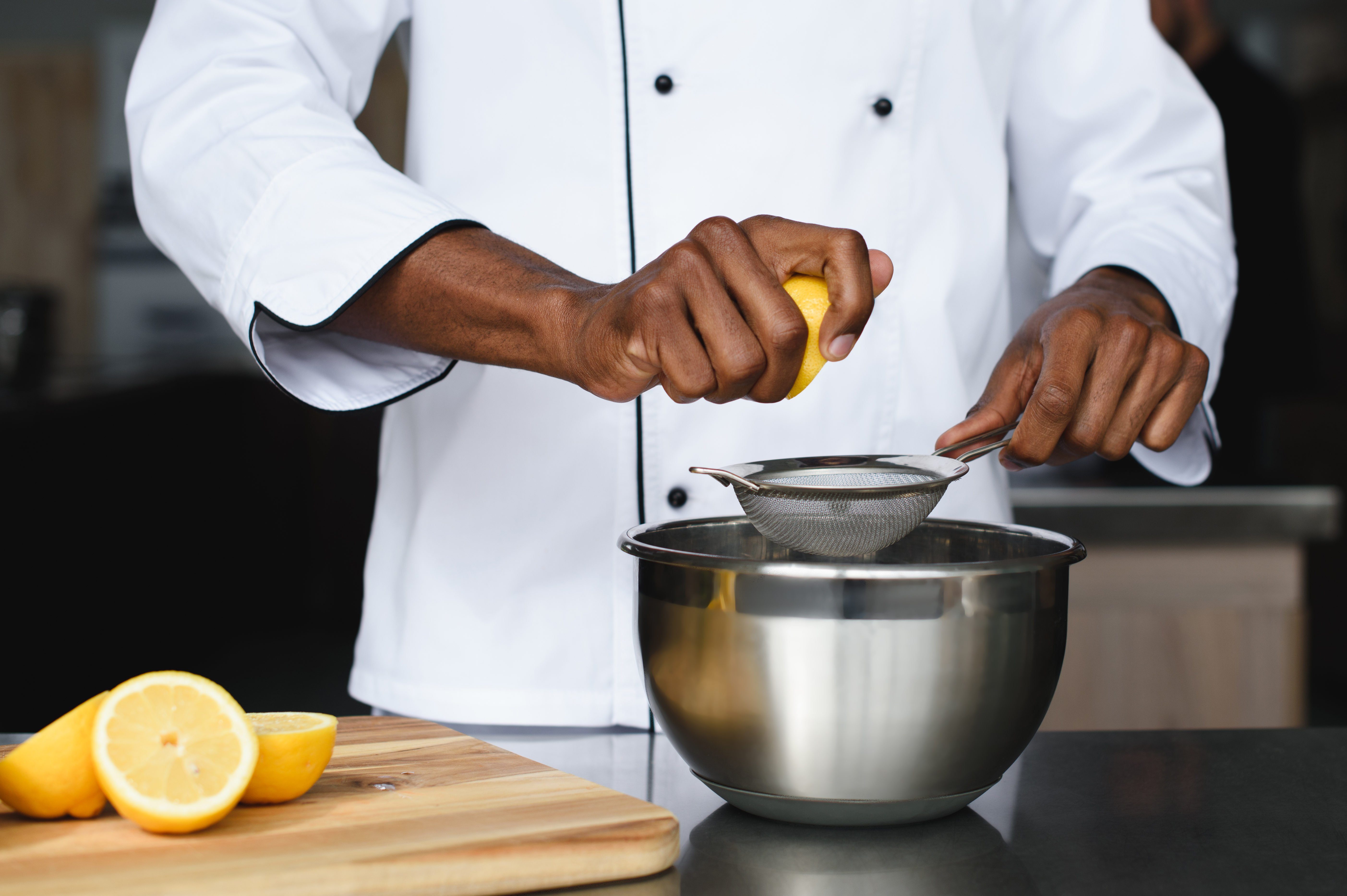 cropped image of african american chef squeezing lemons at restaurant kitchen