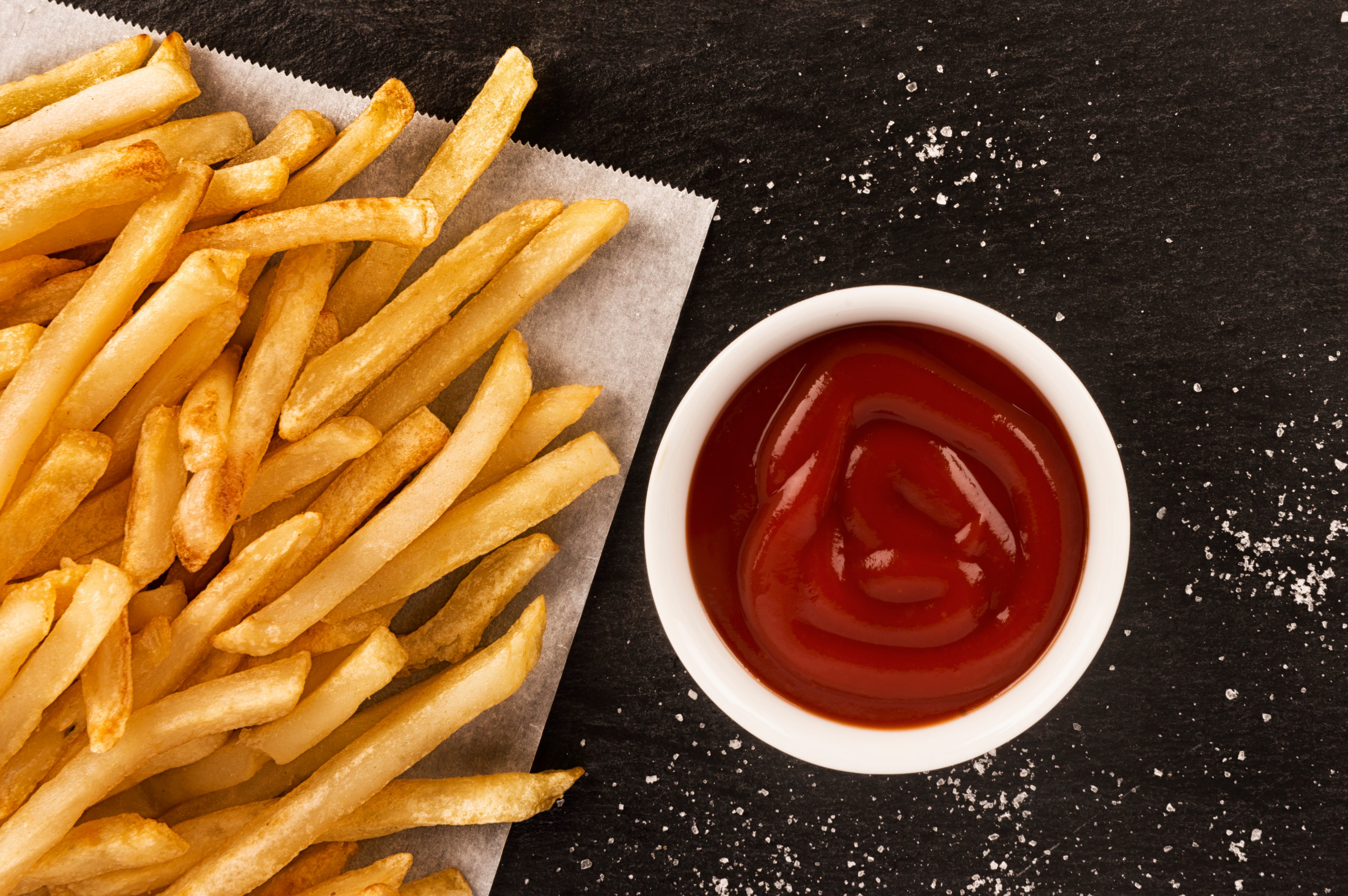 French fries with ketchup on dark background, directly above.
