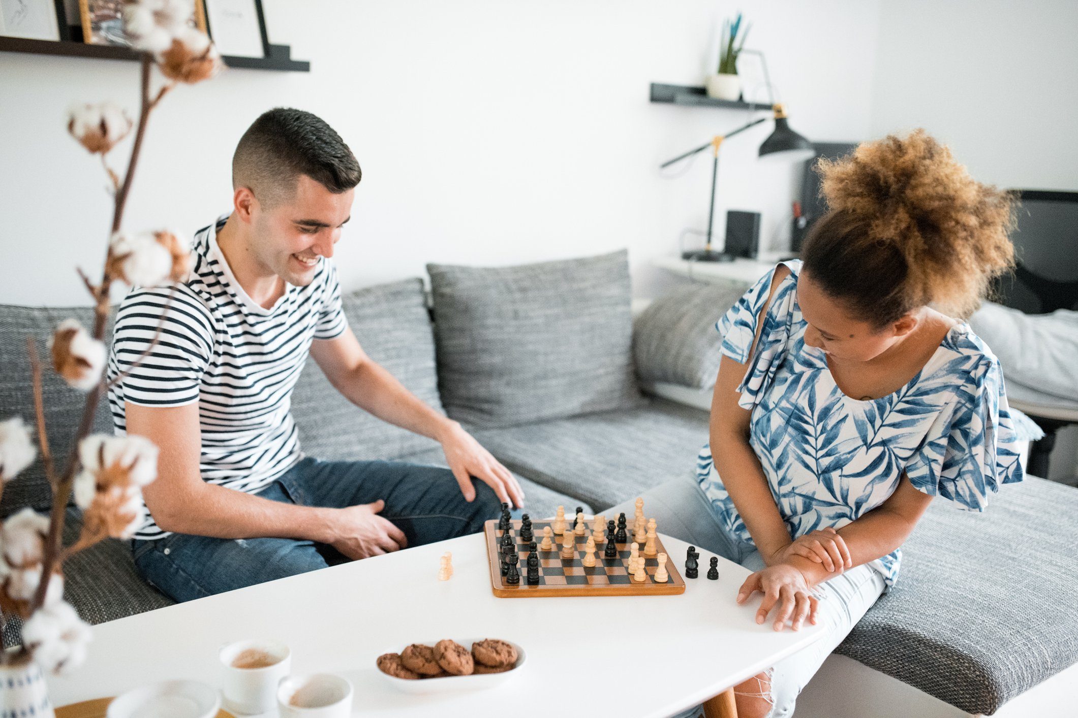 Young heterosexual couple sitting in the living room and playing chess
