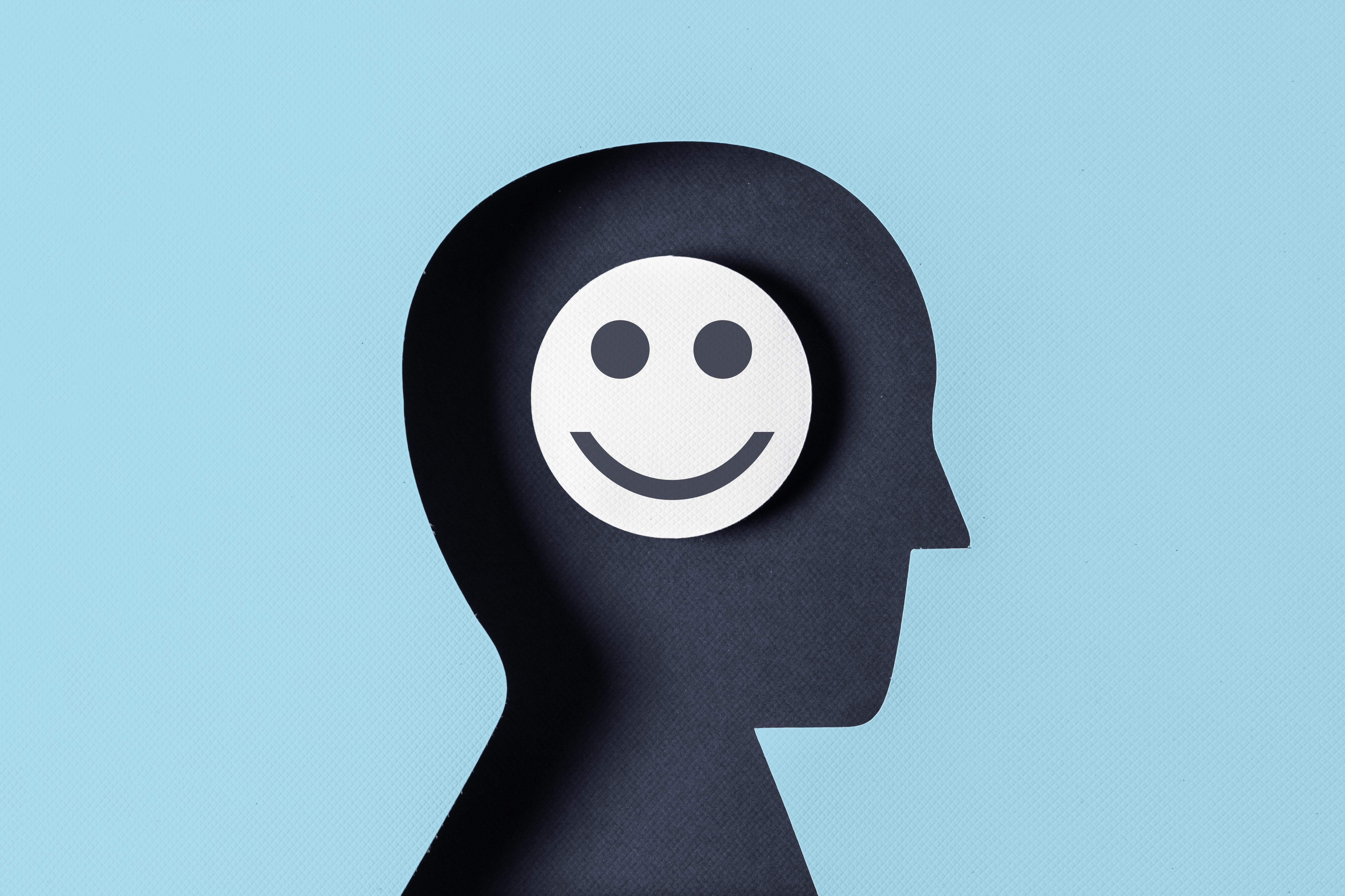 head paper silhouette with smiling face in the brain