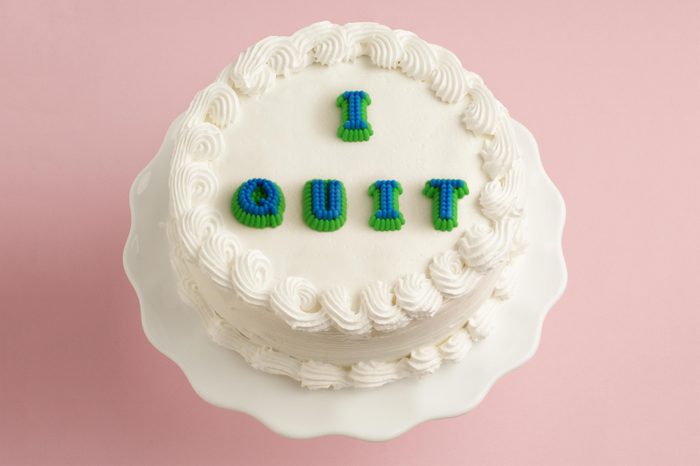 white cake on pink background with "i quit" on the cake