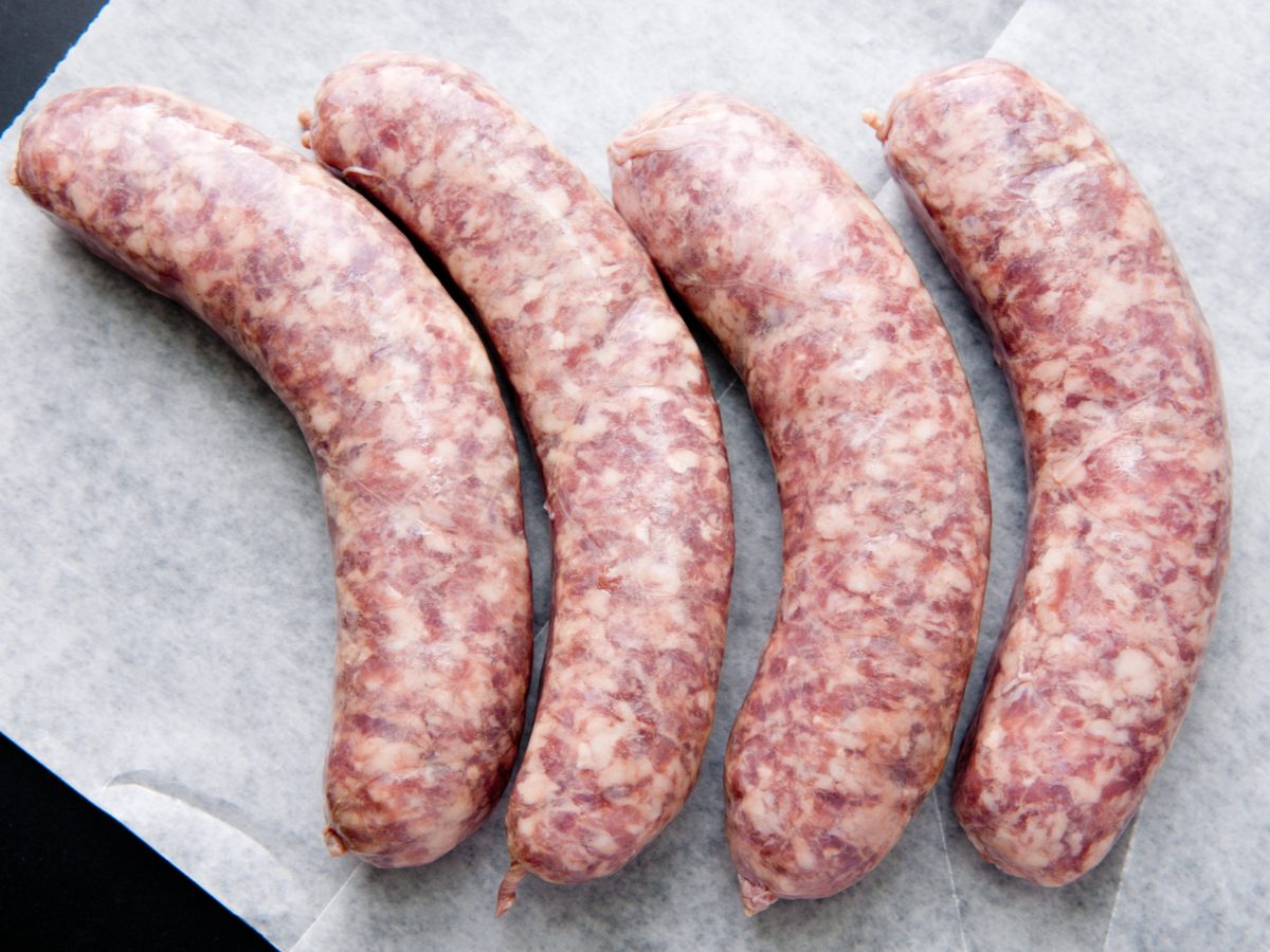 Four uncooked sausages on paper