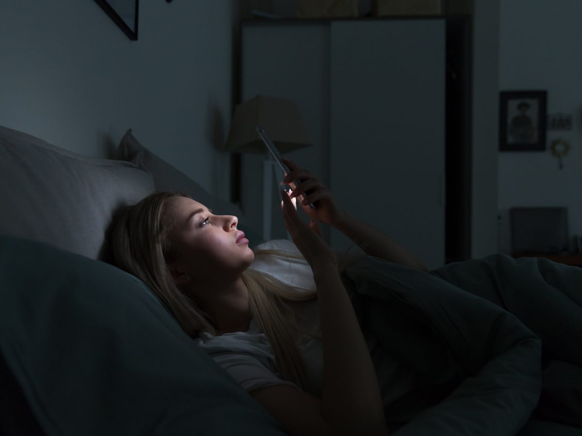 Woman using her smartphone in bed