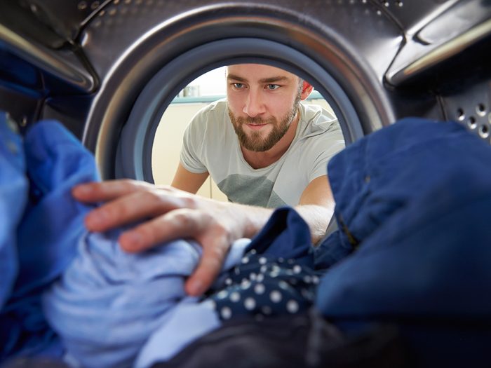 laundry tips - man reaching into dryer