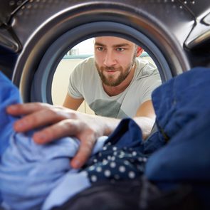 laundry tips - man reaching into dryer