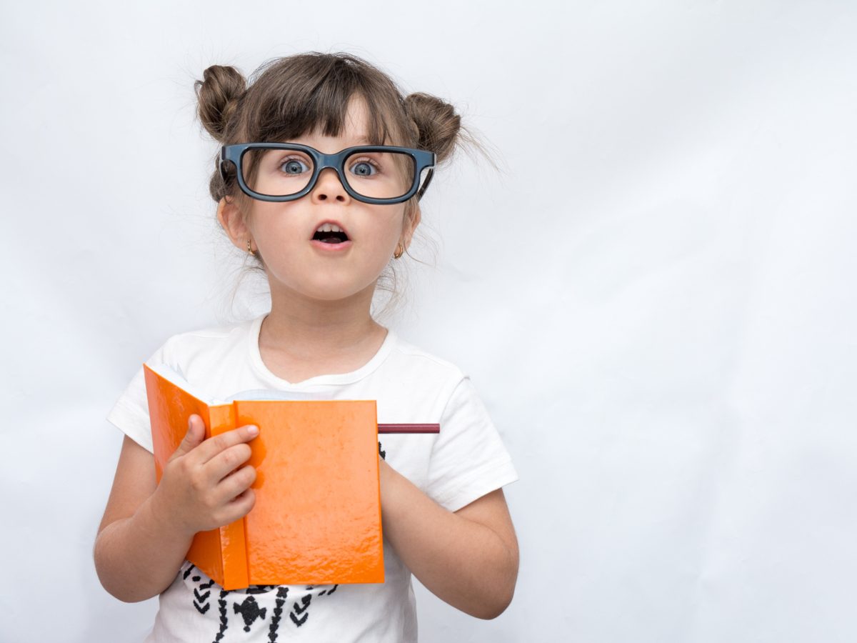 Funny little girl with fake glasses writing in a journal