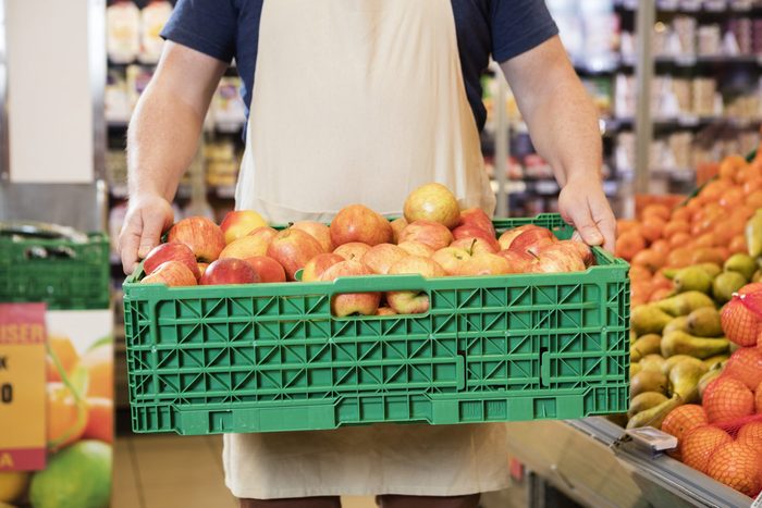 Produce section - Worker carrying crate of apples