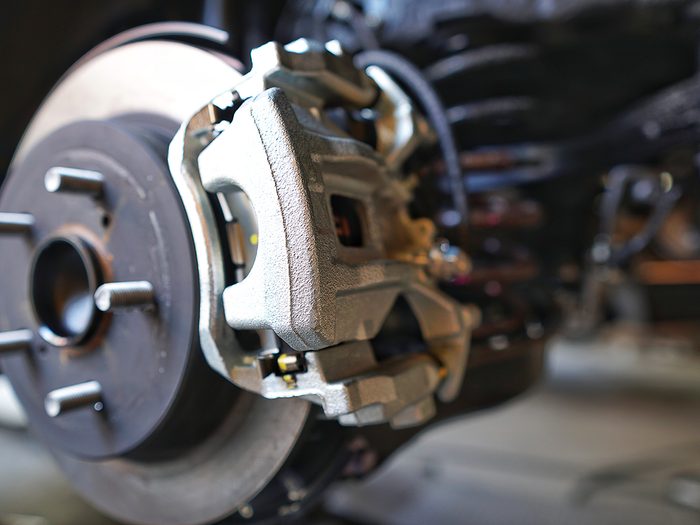 What is a brake caliper - Selective focus of Brake Disc of the vehicle for repair.Automobile mechanic in process of new tire replacement.Car brake repairing in garage.Car Service and technician concept.