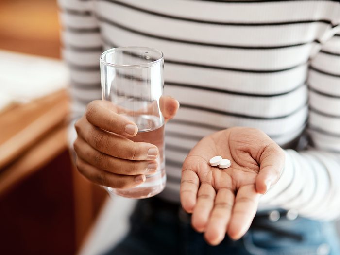 Woman taking new prescription pills with water