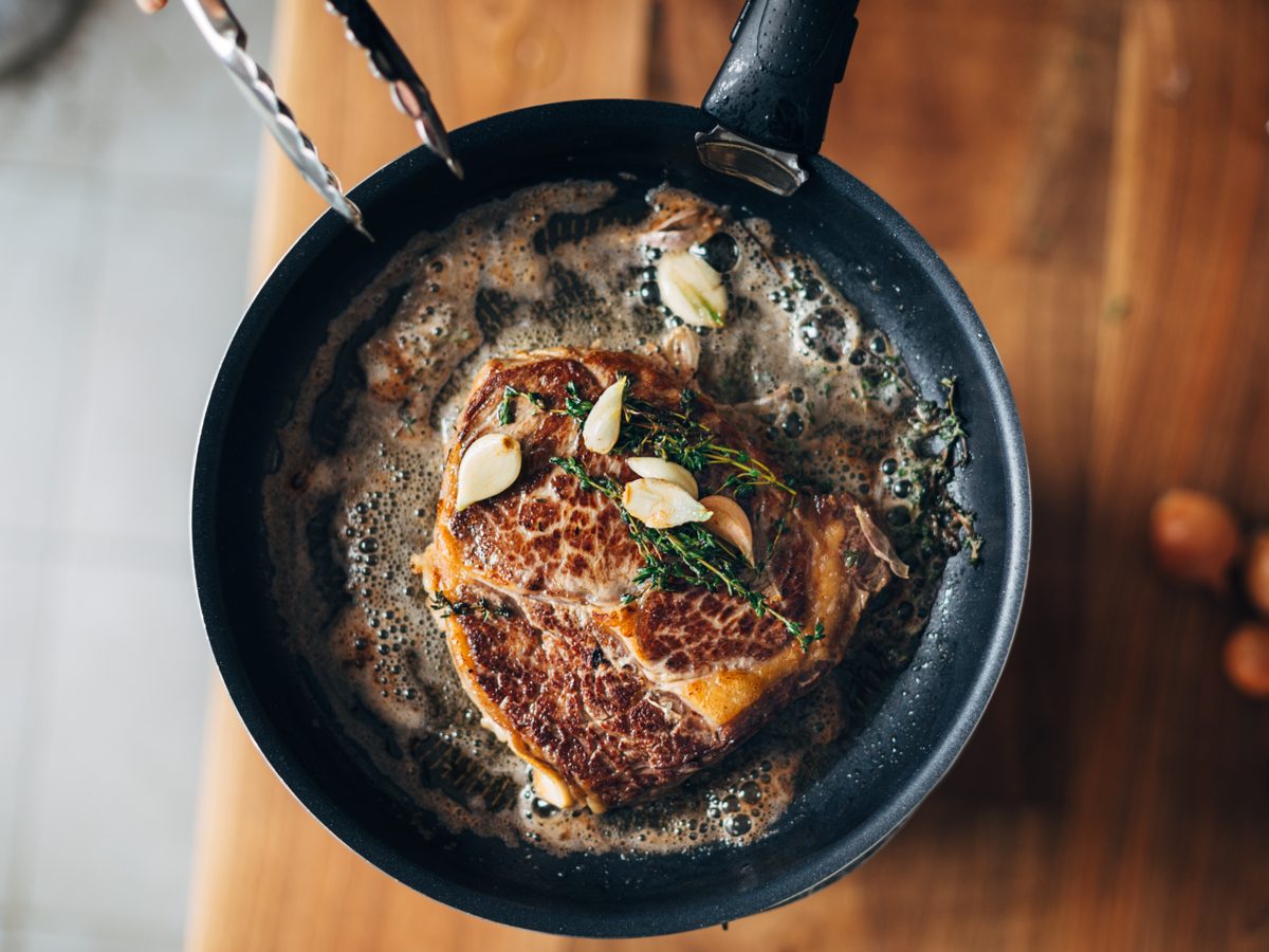 Ribeye steak being seared in cast-iron pan