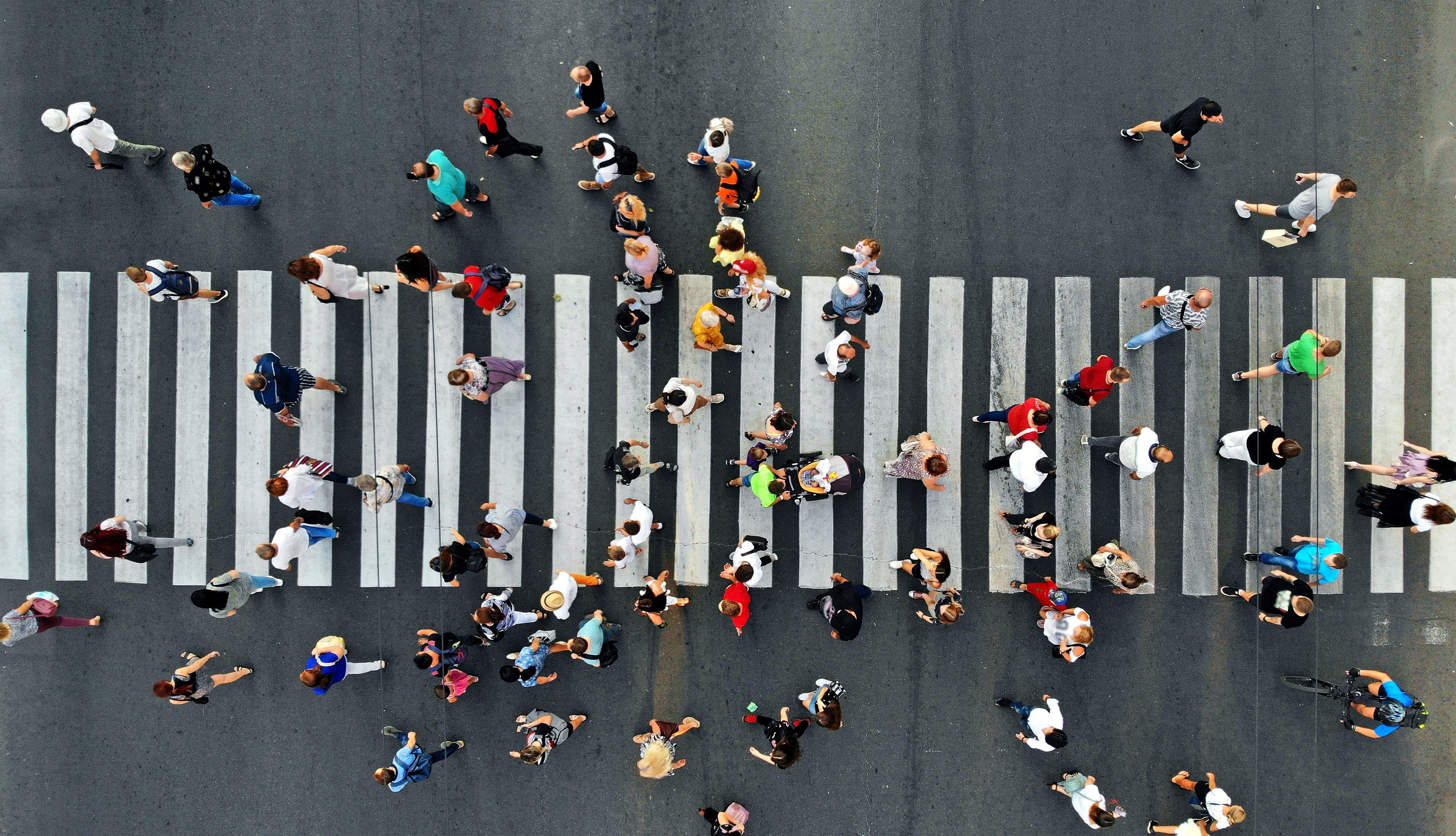 Aerial. People crowd motion through the pedestrian crosswalk. Top view from drone.
