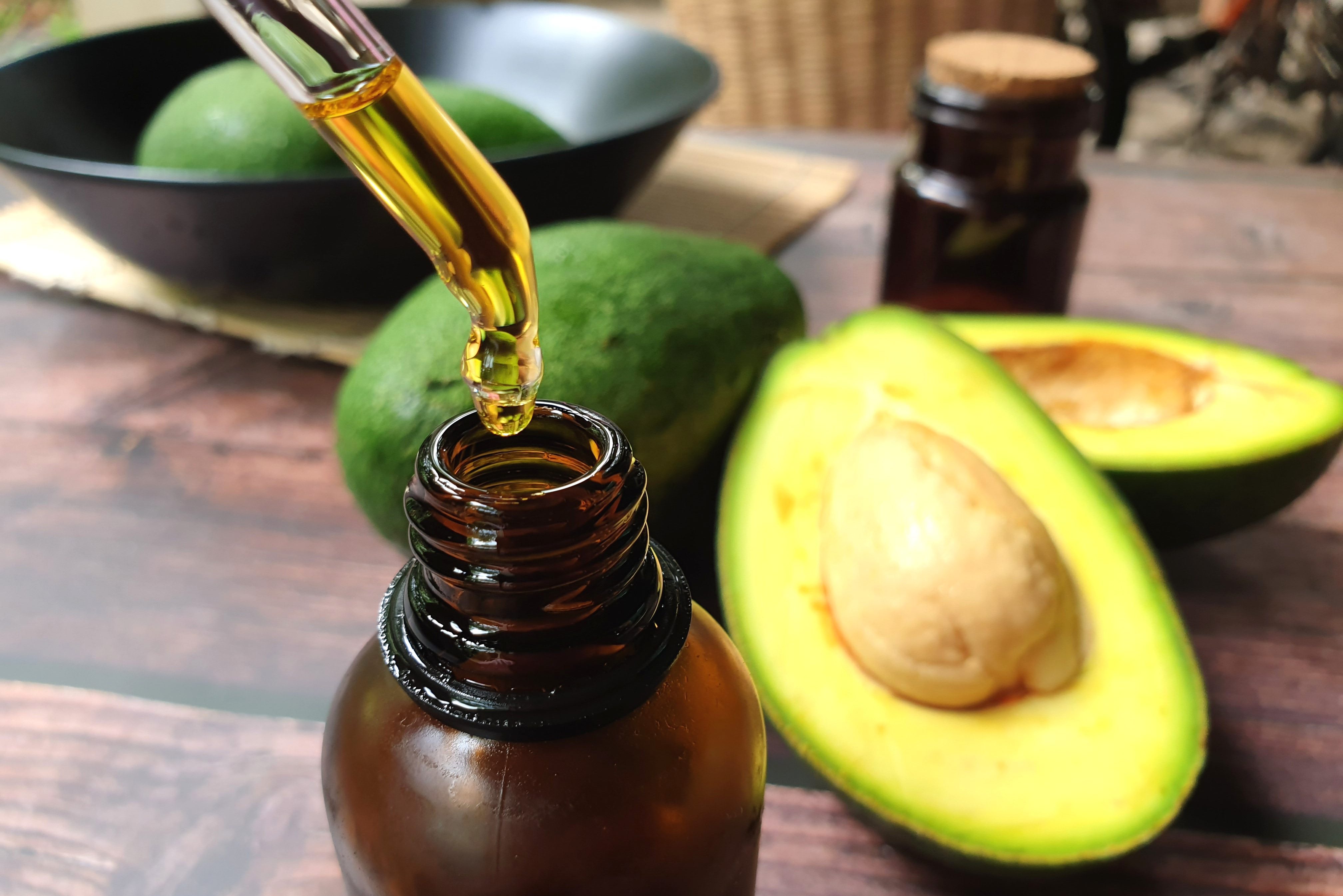 Avocados And Avocado Oil On Wooden Table