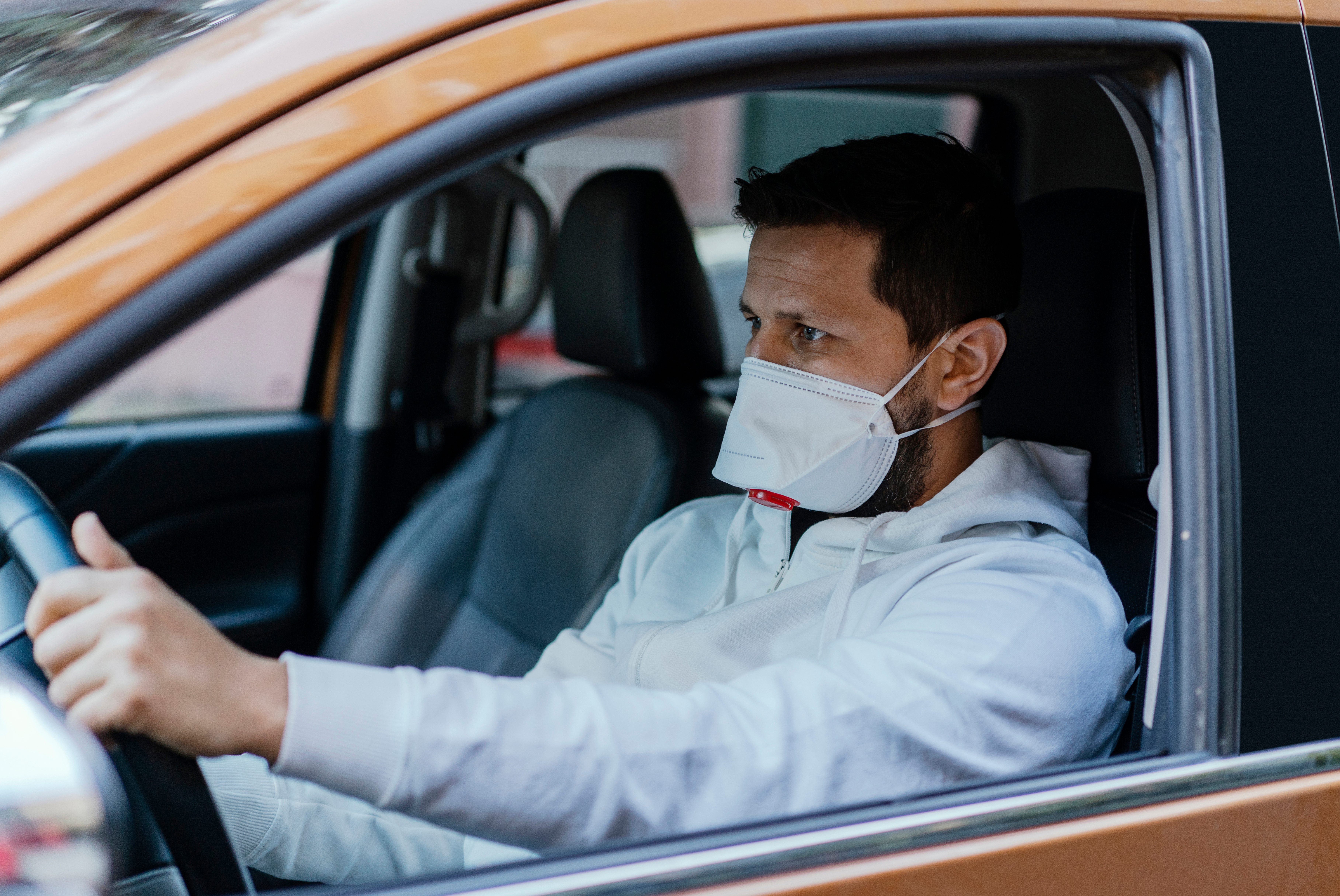 Man driving his car with a protection mask in the city