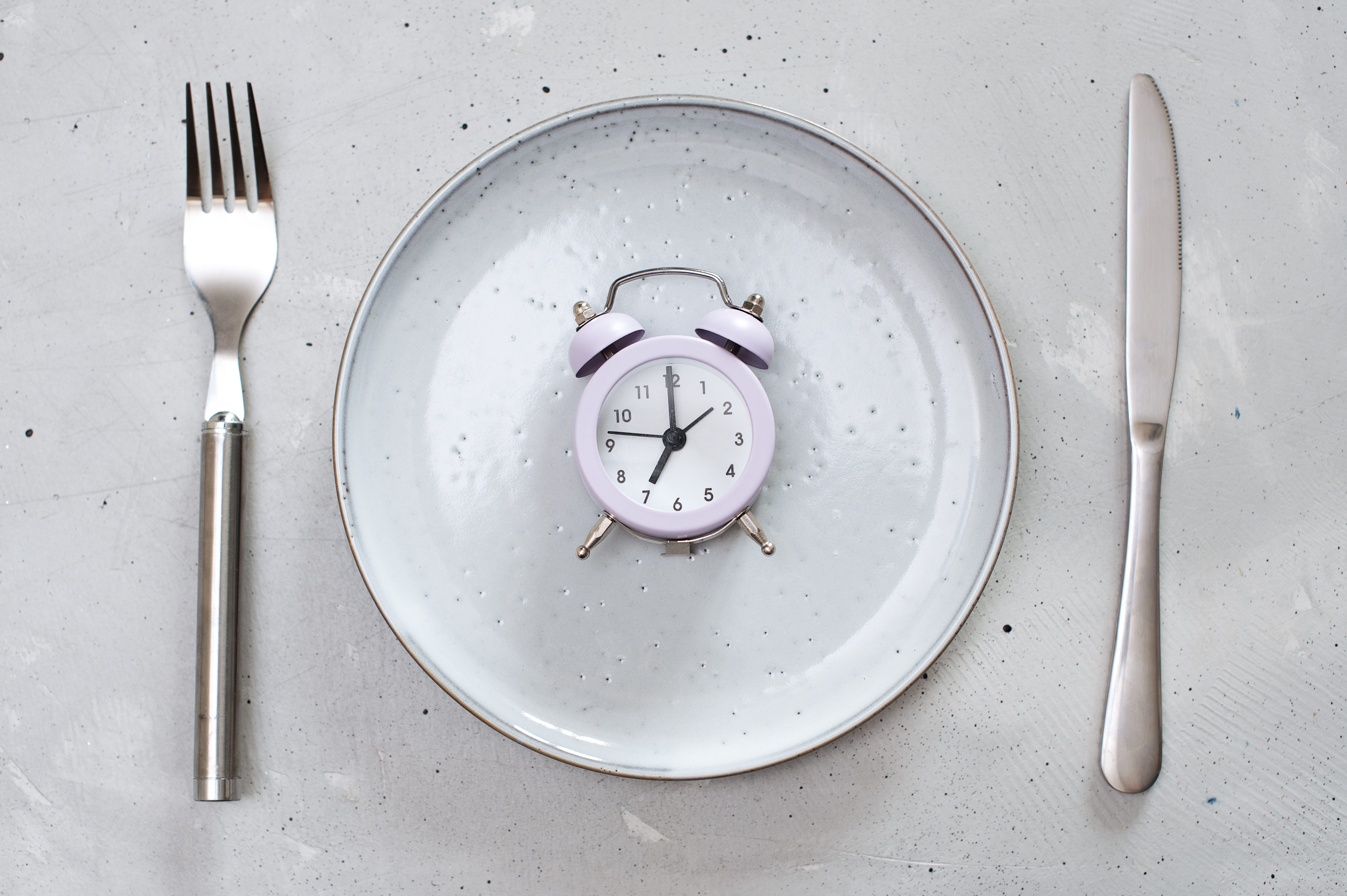 breakfast time concept with alarm clock plate, fork, knife, spoon,