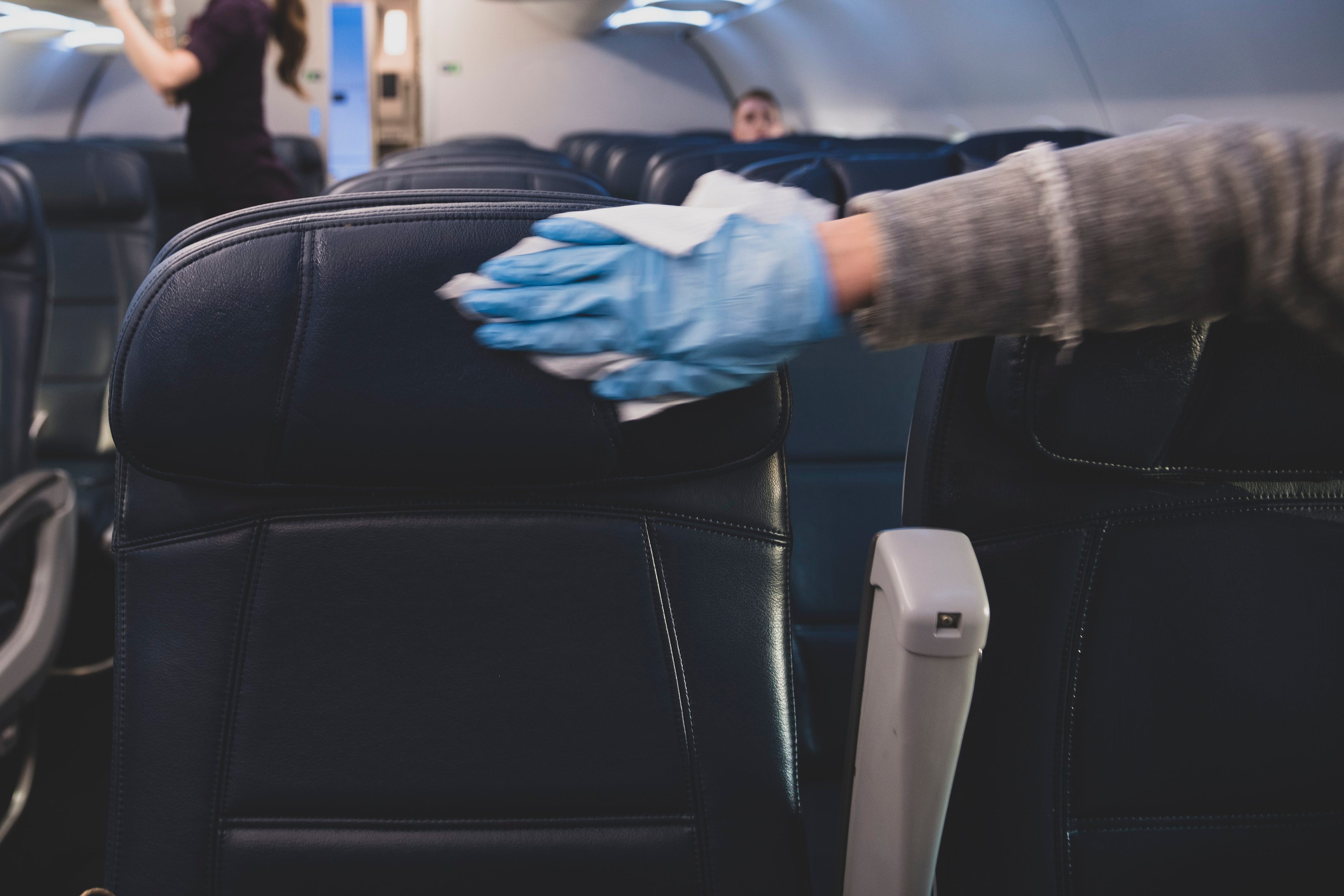 Passenger disinfecting airplane seats after boarding flight