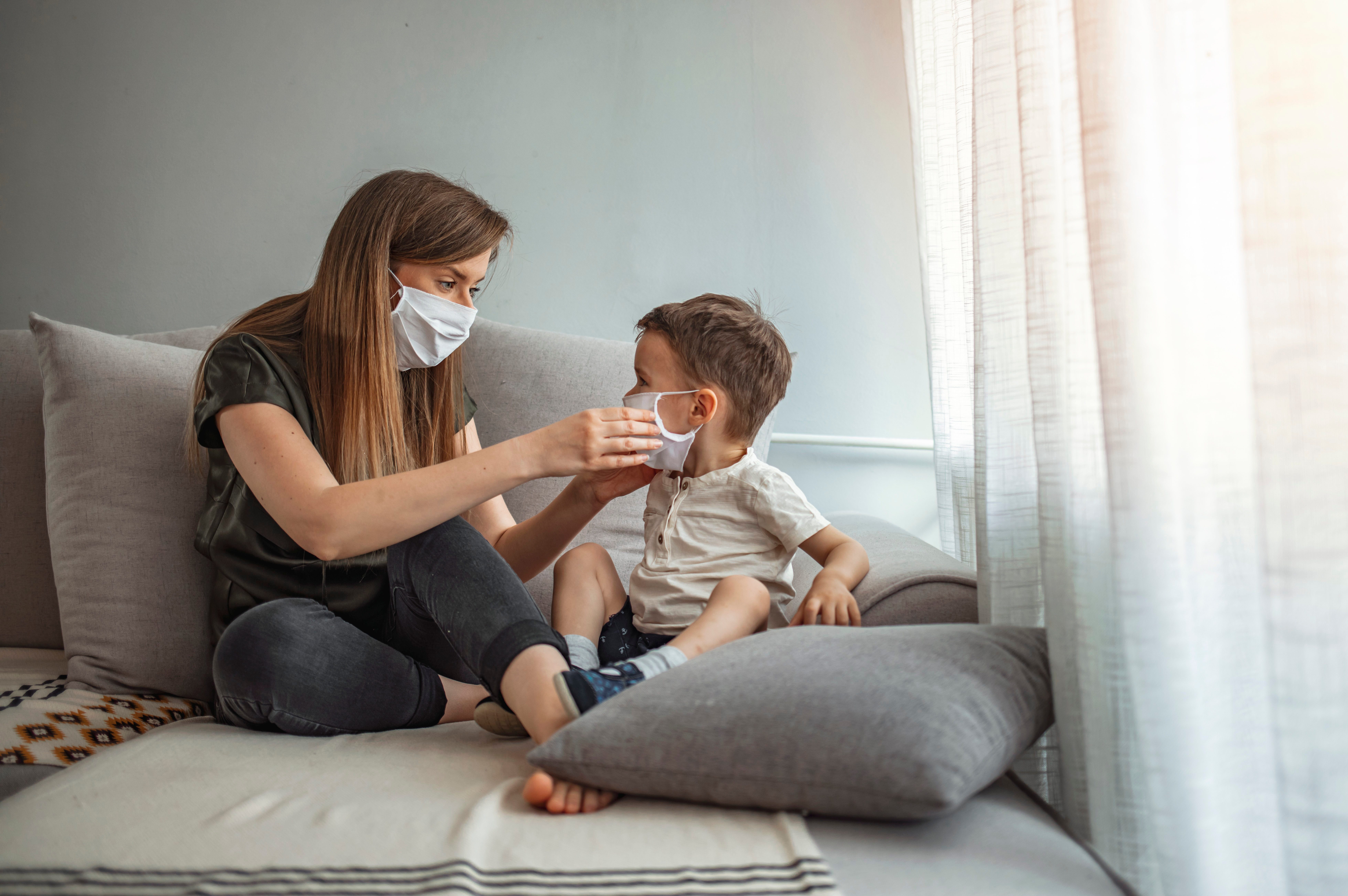 Mother putting protective face mask on her child.