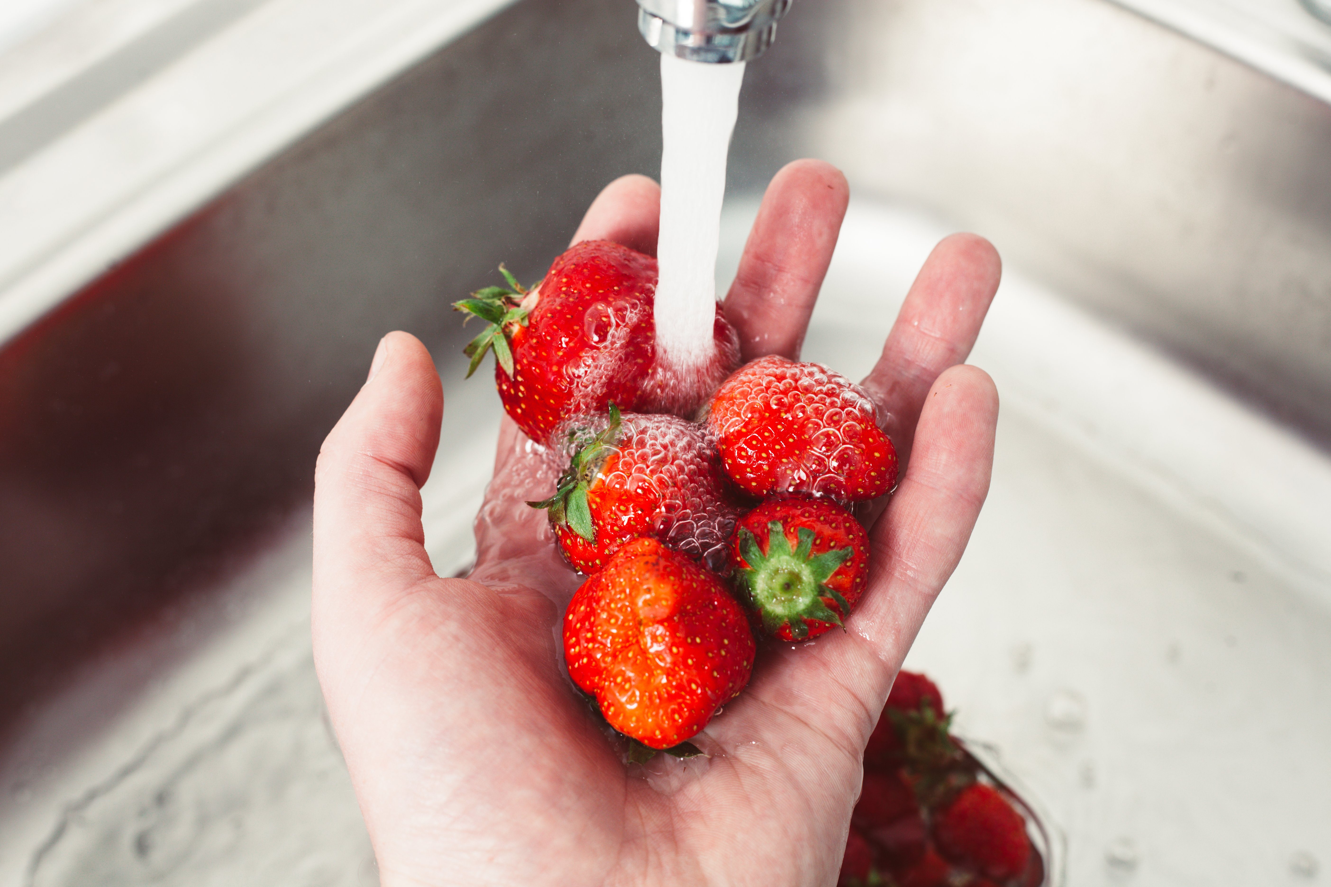 Strawberries in hands under the water. Pure fruit is health