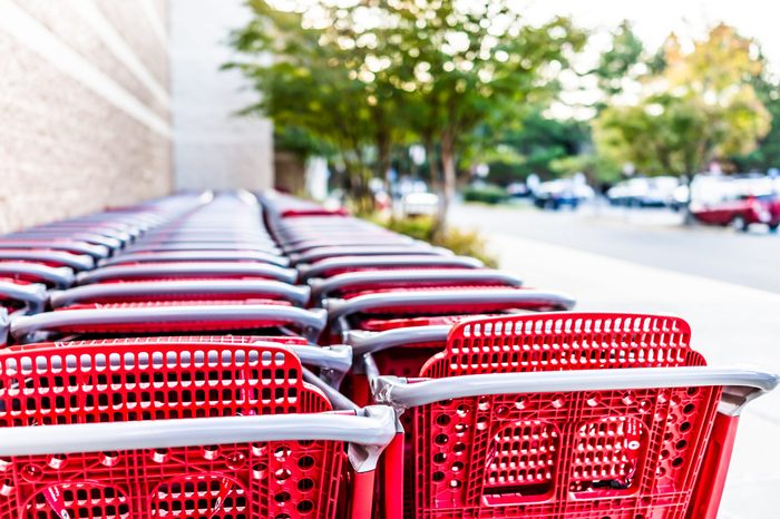 Many rows of red shopping carts outside by store with closeup by parking lot