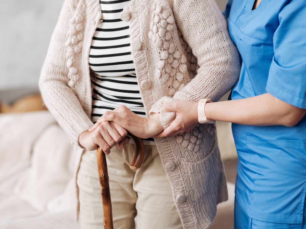 Nurse helping senior woman stand at her home