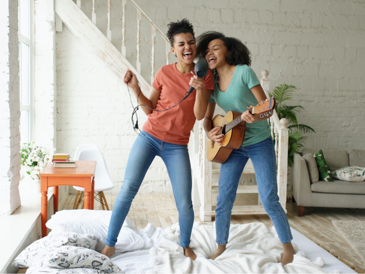 Two female friends having a dance party in their home
