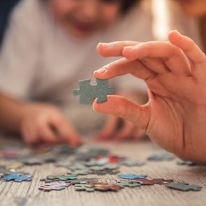 Child finishing jigsaw puzzle with parents