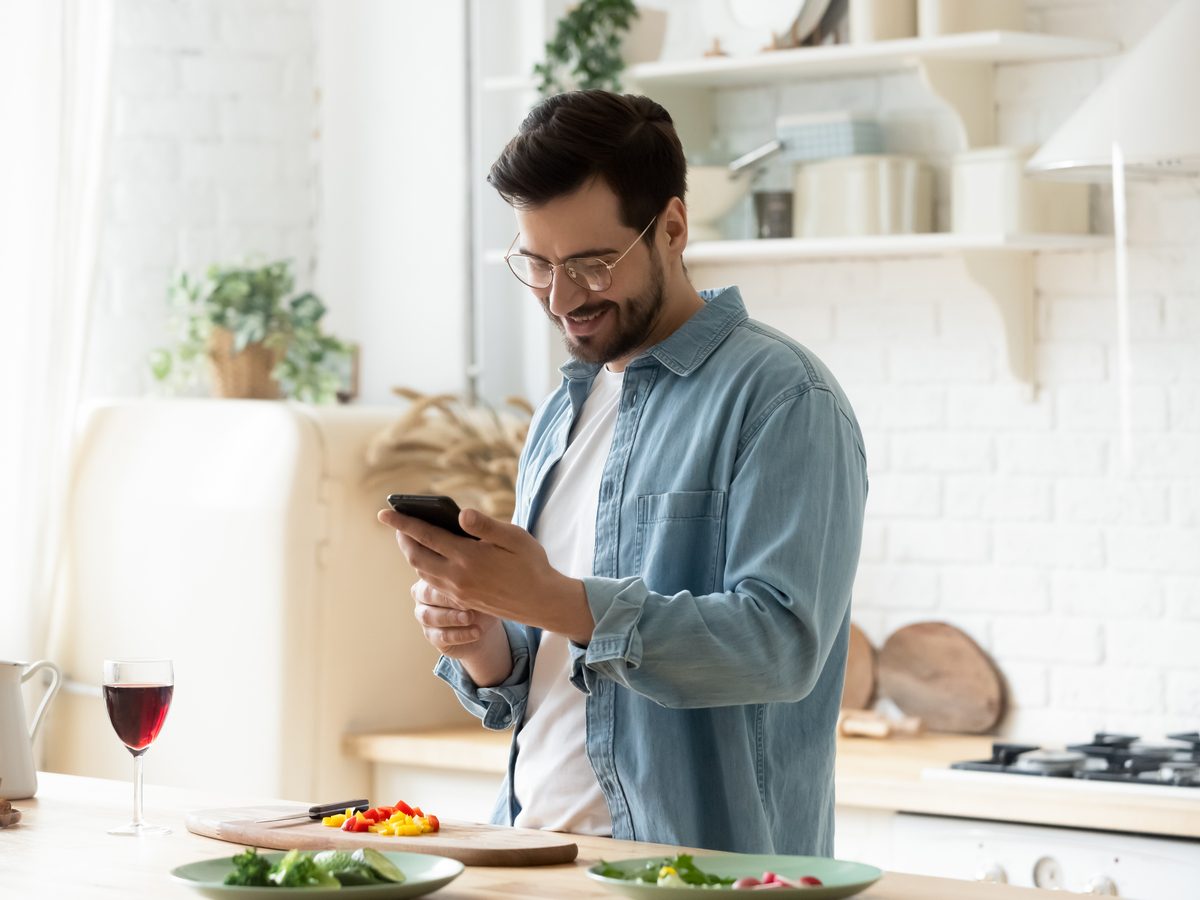 Millennial male in his kitchen using his smartphone