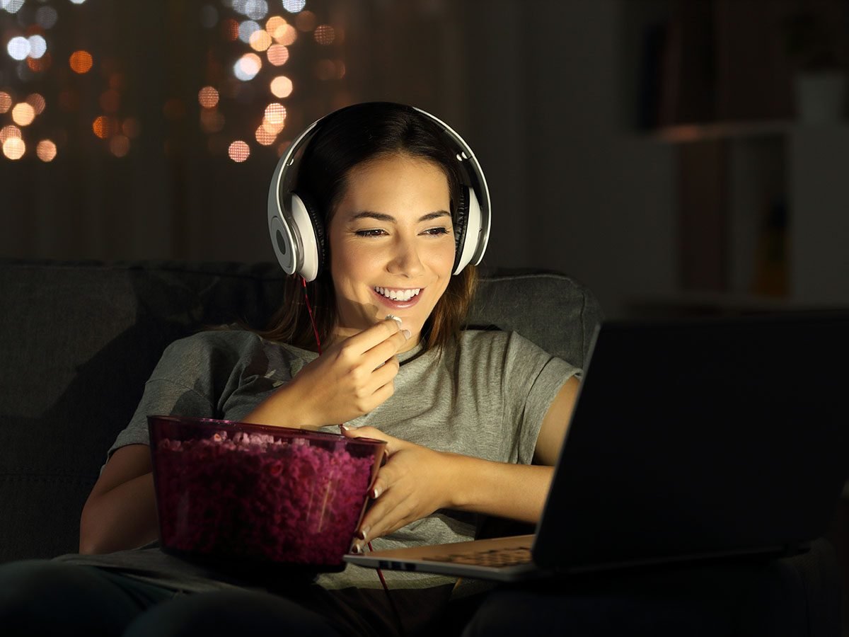 women watching film on laptop while eating popcorn.