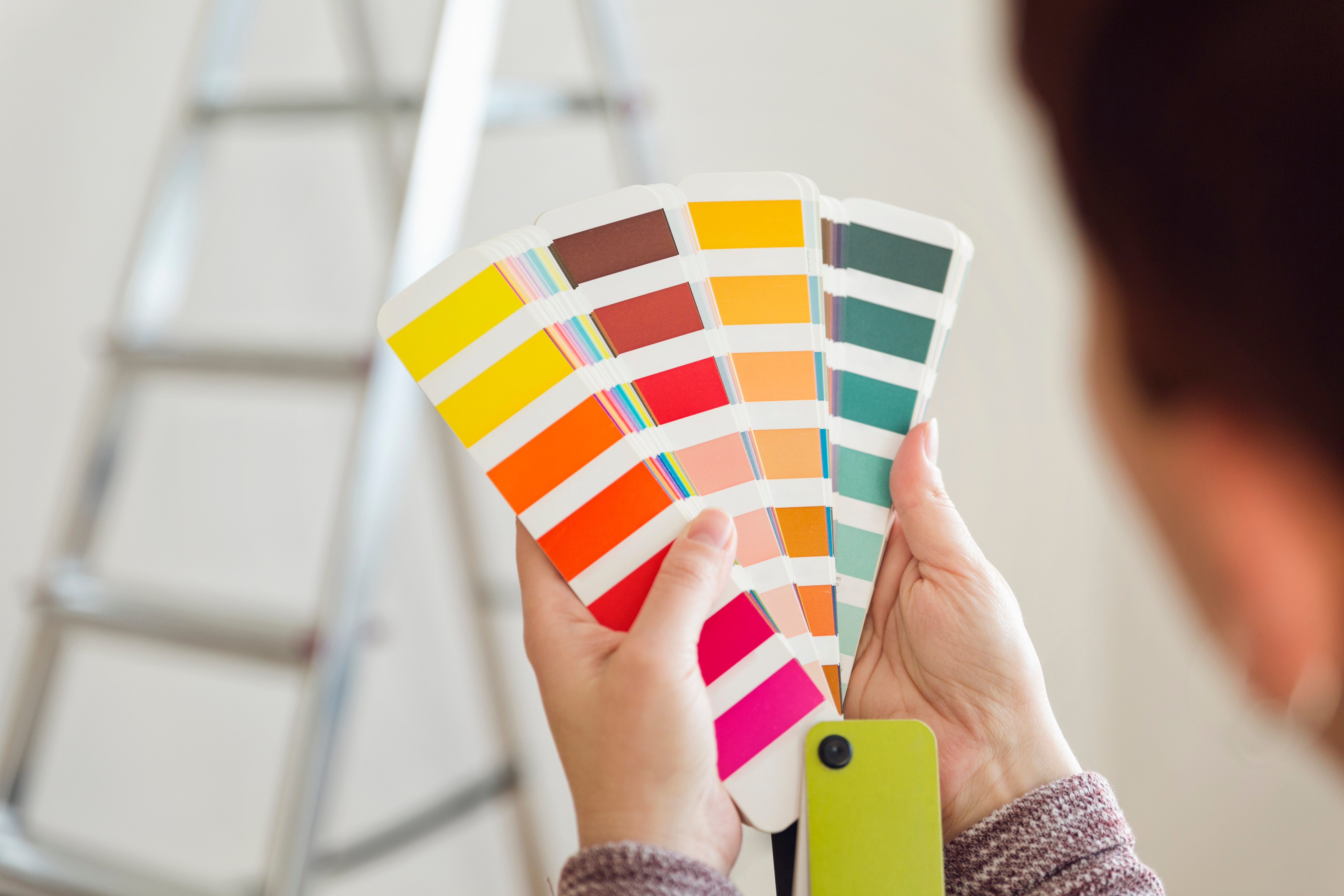 Woman holding colour sample in an empty room with a ladder