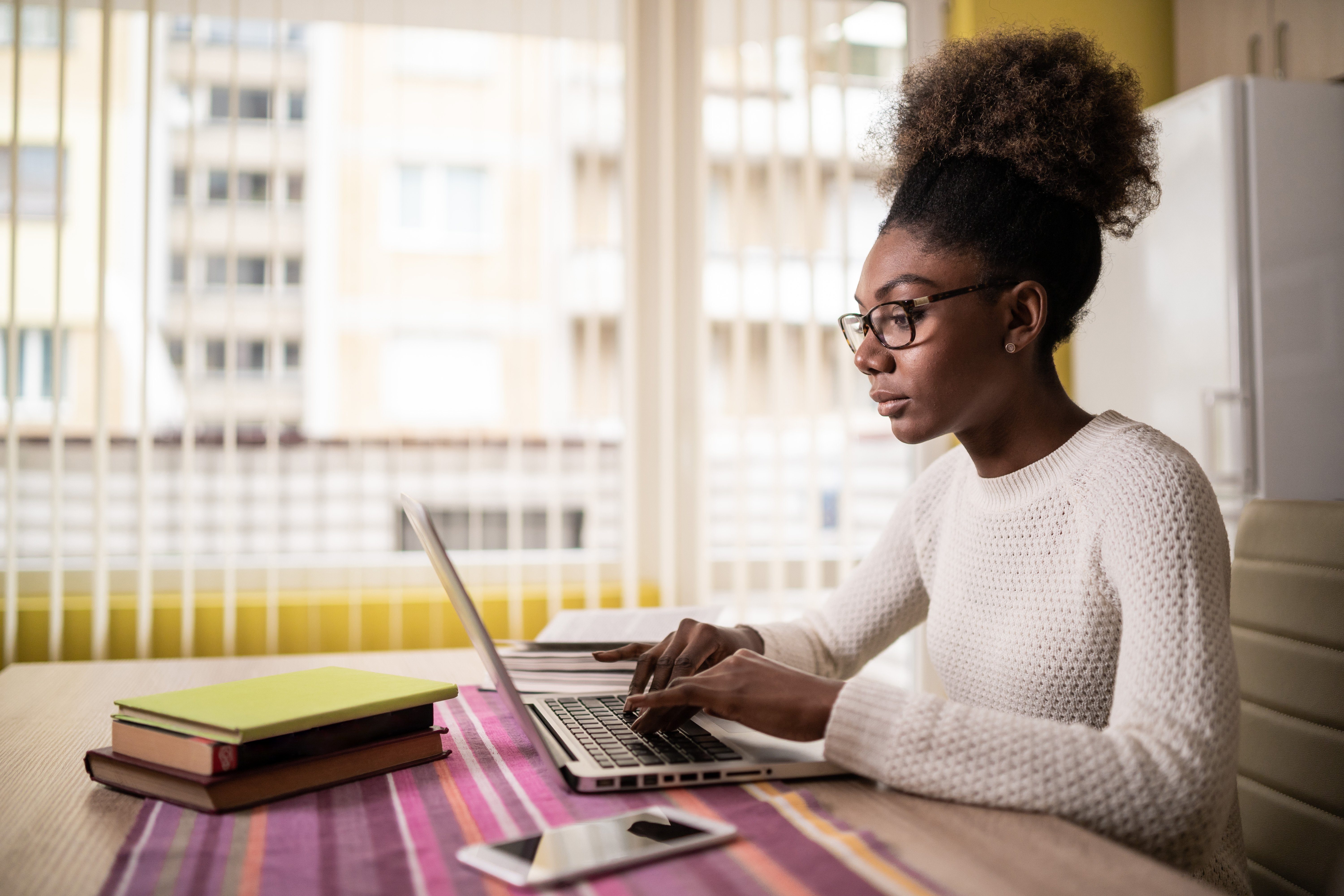 Afro Woman sitting at home using laptop and studying