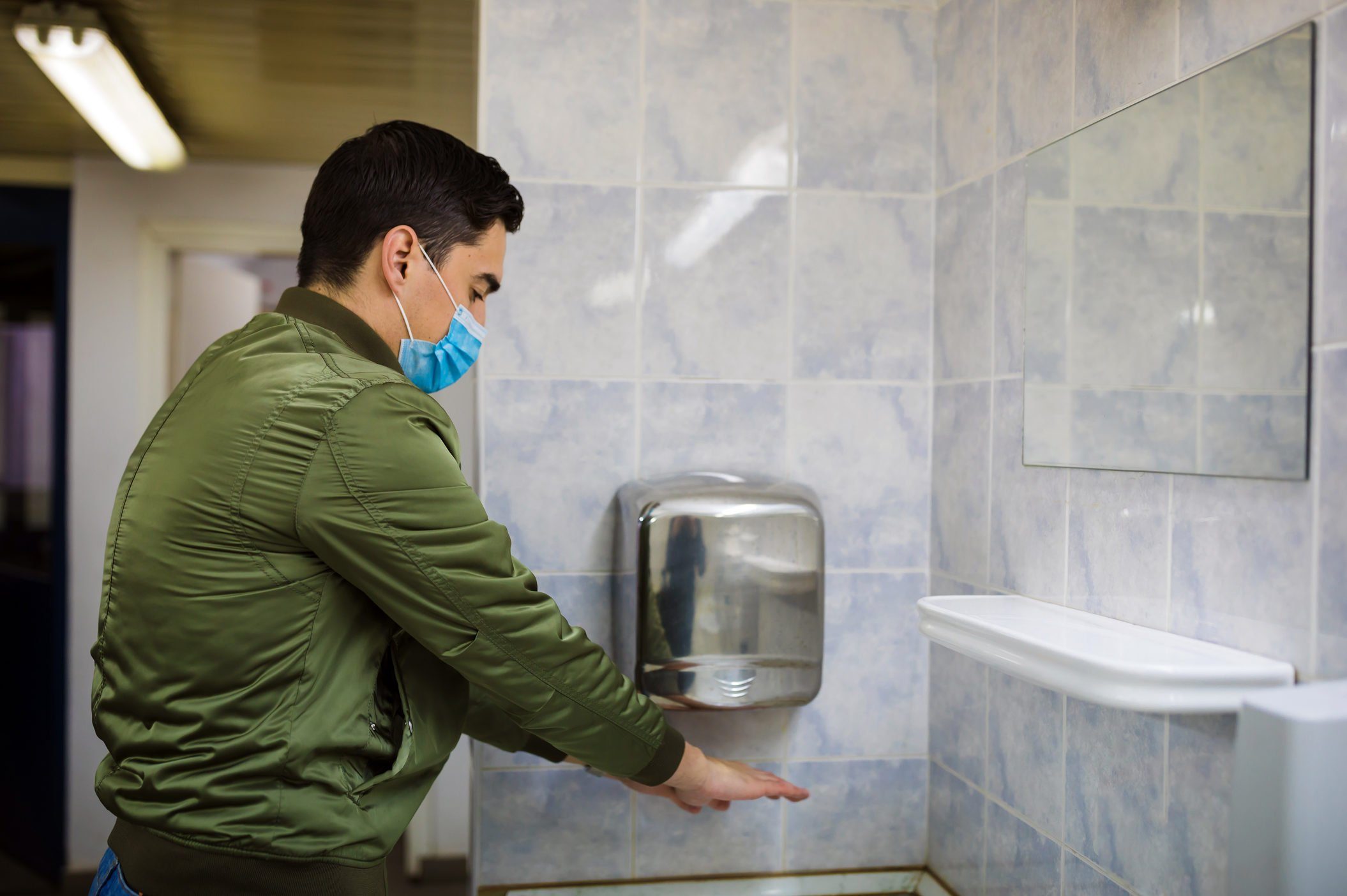 Man dries wet hands with an electric hand dryers