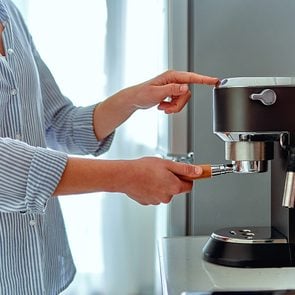 Coffee maker mistakes - Female hands holding portafilter and making fresh aromatic coffee at home using a modern coffee maker