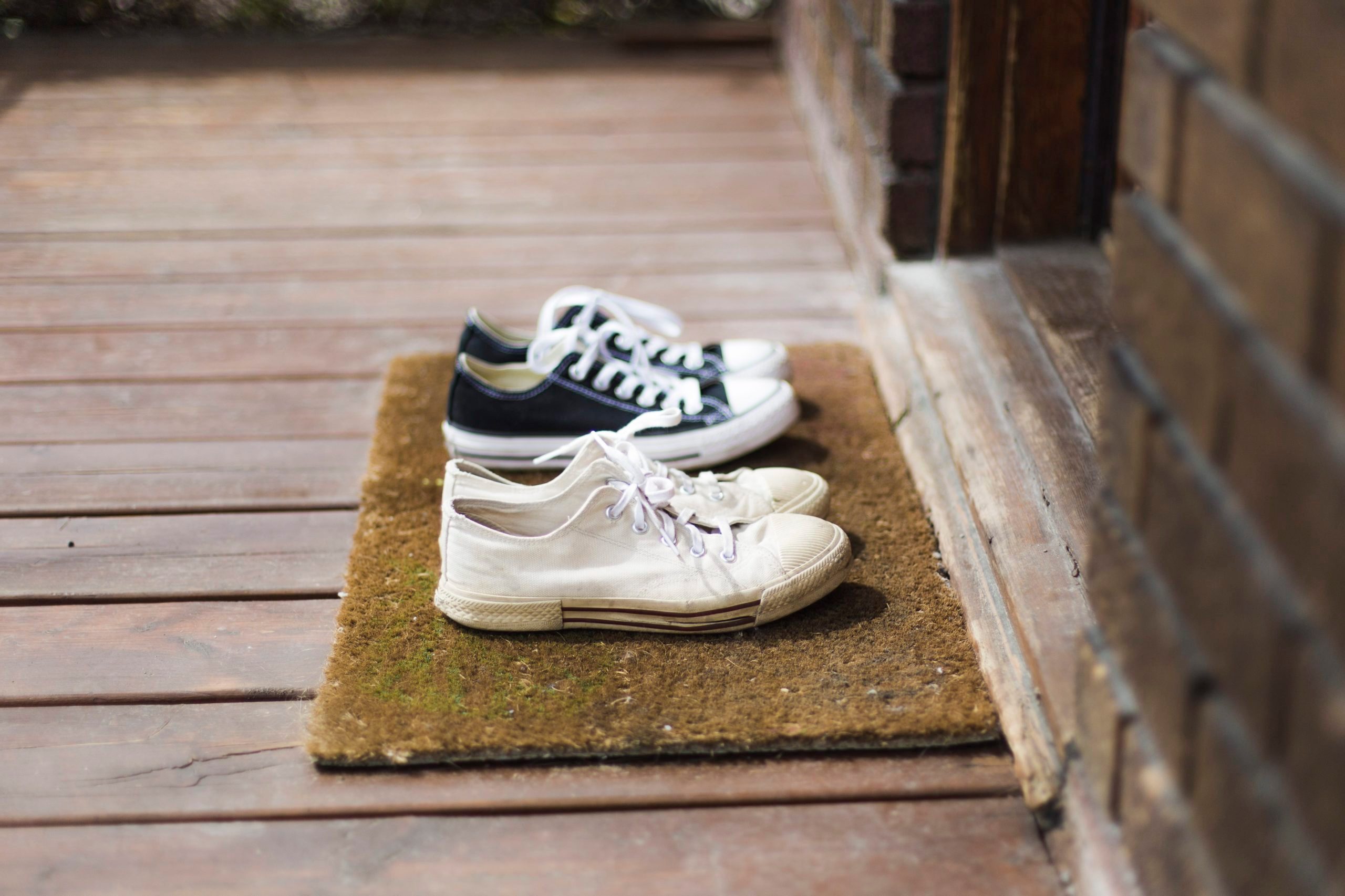 Two pairs of black and white sneakers shoes on a porch