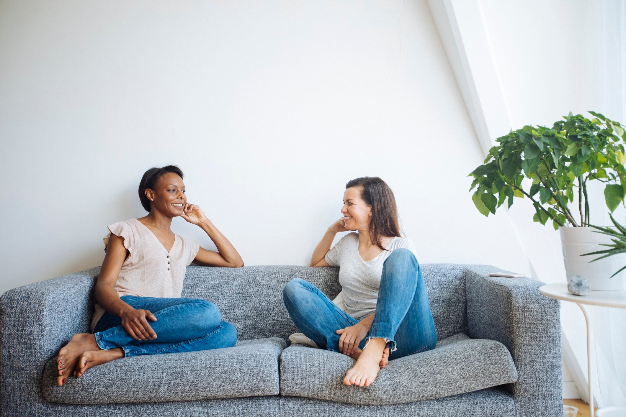 Two relaxed women sitting on couch at home talking