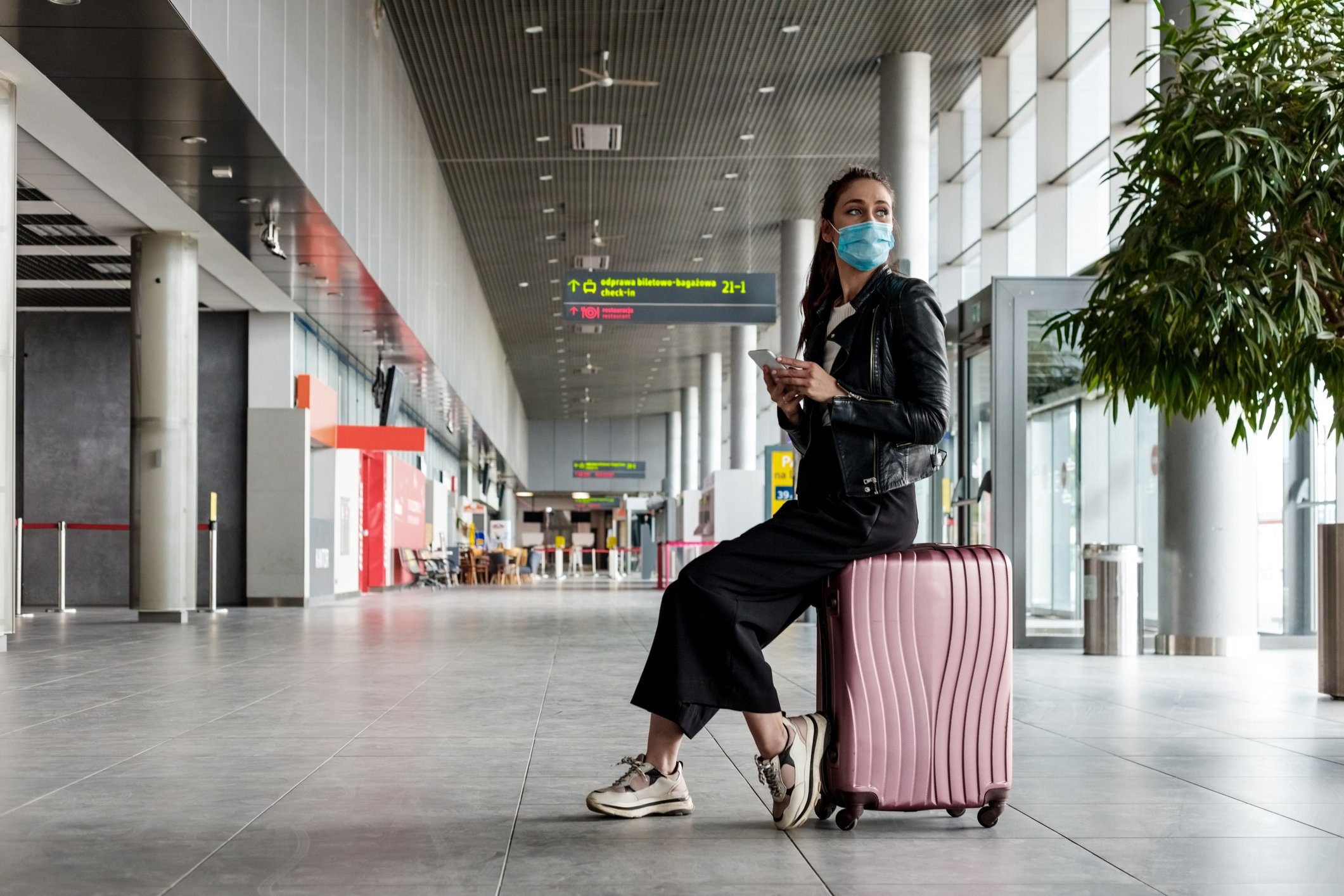 Young woman at the airport with luggage, wearing N95 face masks