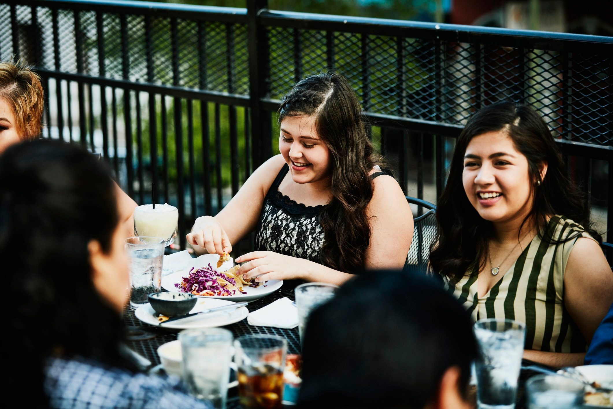 Laughing young women sharing a meal with family on restaurant deck