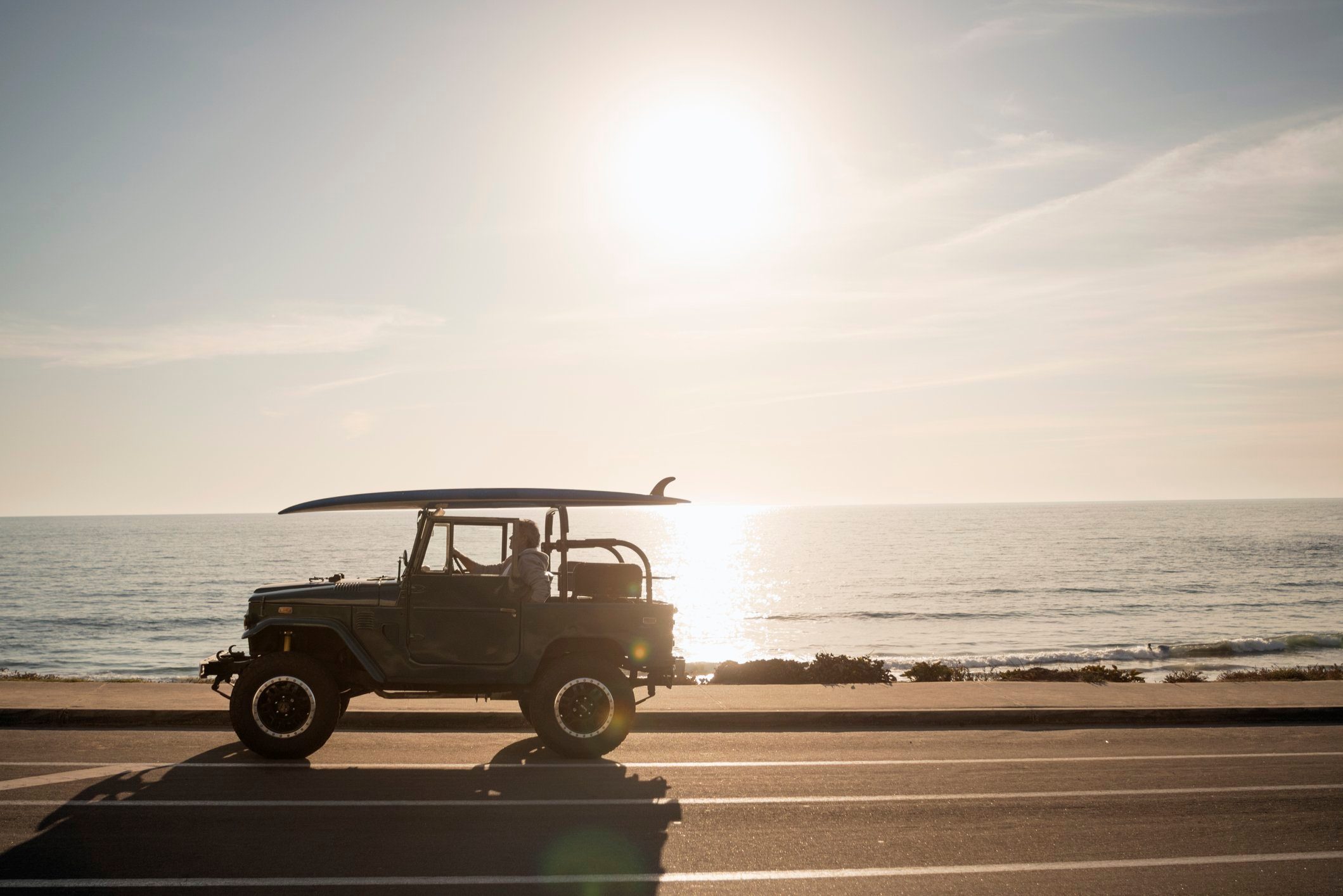 Mature man sitting in his Land Cruiser by the beach