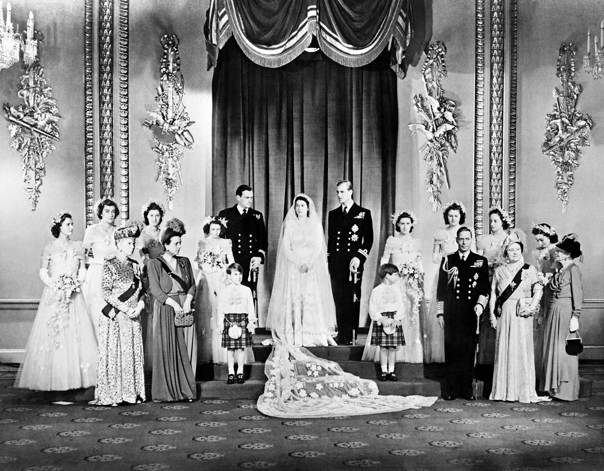 Members of the British Royal family and guests pose around Princess Elizabeth (future Queen Elizabeth II) (CL) and Philip, Duke of Edinburgh (CR) (future Prince Philip); at right the group includes Britain's King George VI (5R) stood next to Queen Elizabeth (3R) with Princess Alice of Athlone (R) and in front of bridemaids that include Princess Margaretb (7R) stood next to Philip; at left the group includes the best man David Mountbatten, Marquess of Milford Haven (7L) stood next to Princess Elizabeth, Mary of Teck (3L), mother of King George VI, stands at left in front of the bridesmaids next to Princess Alice of Battenberg (5L), Philip's mother; the page boys are Prince William of Gloucester and Prince Michael of Kent; in the Throne Room at Buckingham Palace on their wedding day November 20, 1947