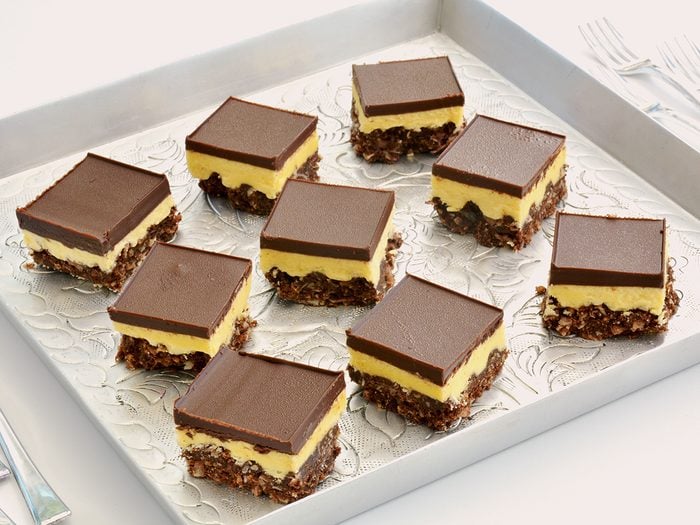 Canadian Food - Fresh baked Nanaimo bars on vintage embossed metal tray and tiny forks in horizontal format.