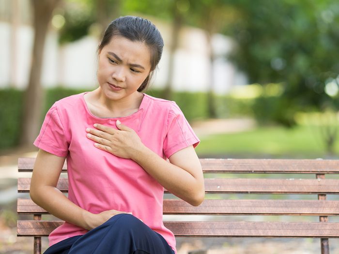 Signs of disease your teeth can reveal - woman with acid reflux sitting on bench