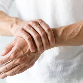 Closeup of male arms holding his painful wrist caused by prolonged work on the computer, laptop. Carpal tunnel syndrome, arthritis, neurological disease concept. Numbness of the hand
