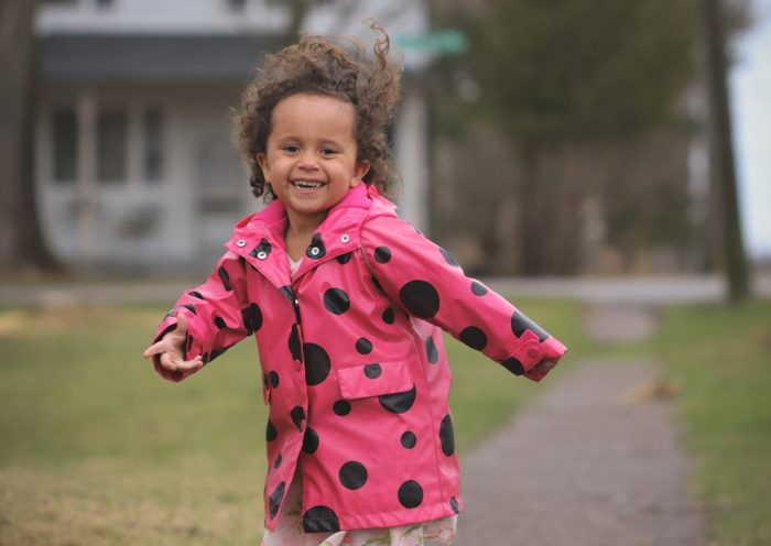 Cute little girl smiling and laughing while running on a sidewalk