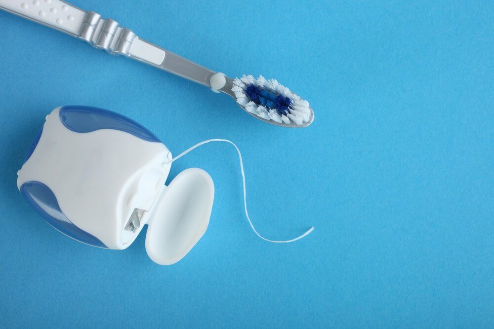 Dental floss and toothbrush on a blue background