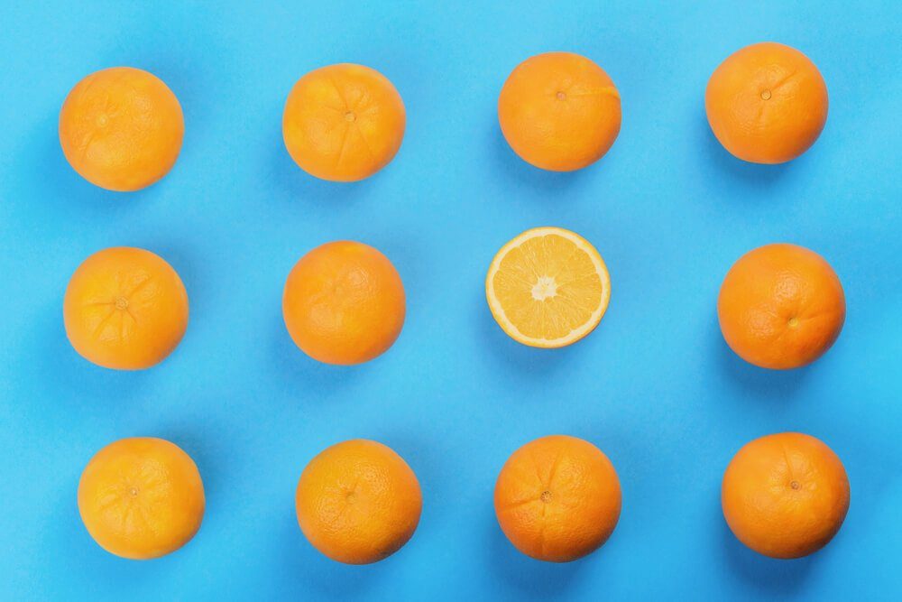 background of orange pattern, one oranges cut in half, top view, blue background, studio shot