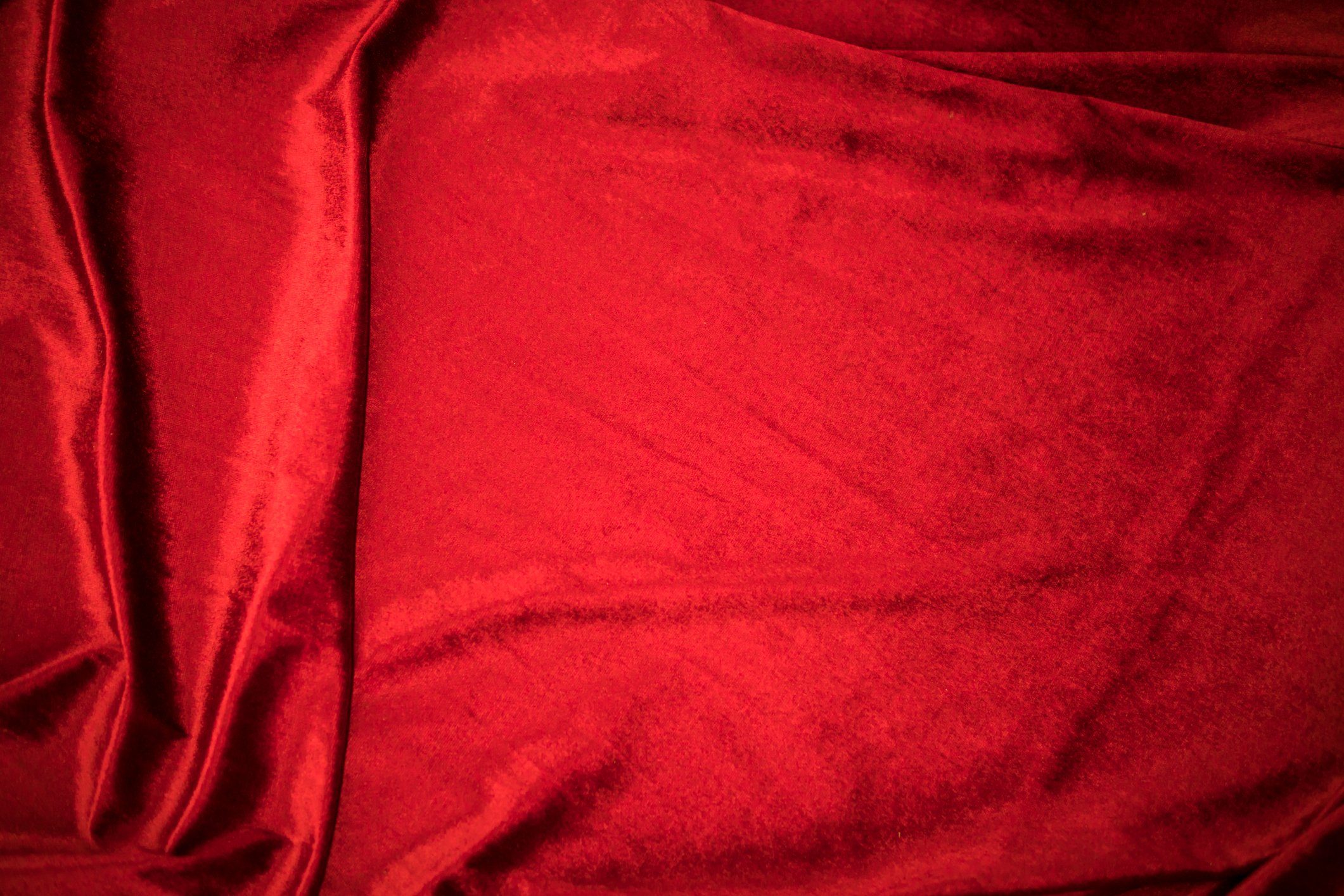Fold soft waved red velour fabric textured background.