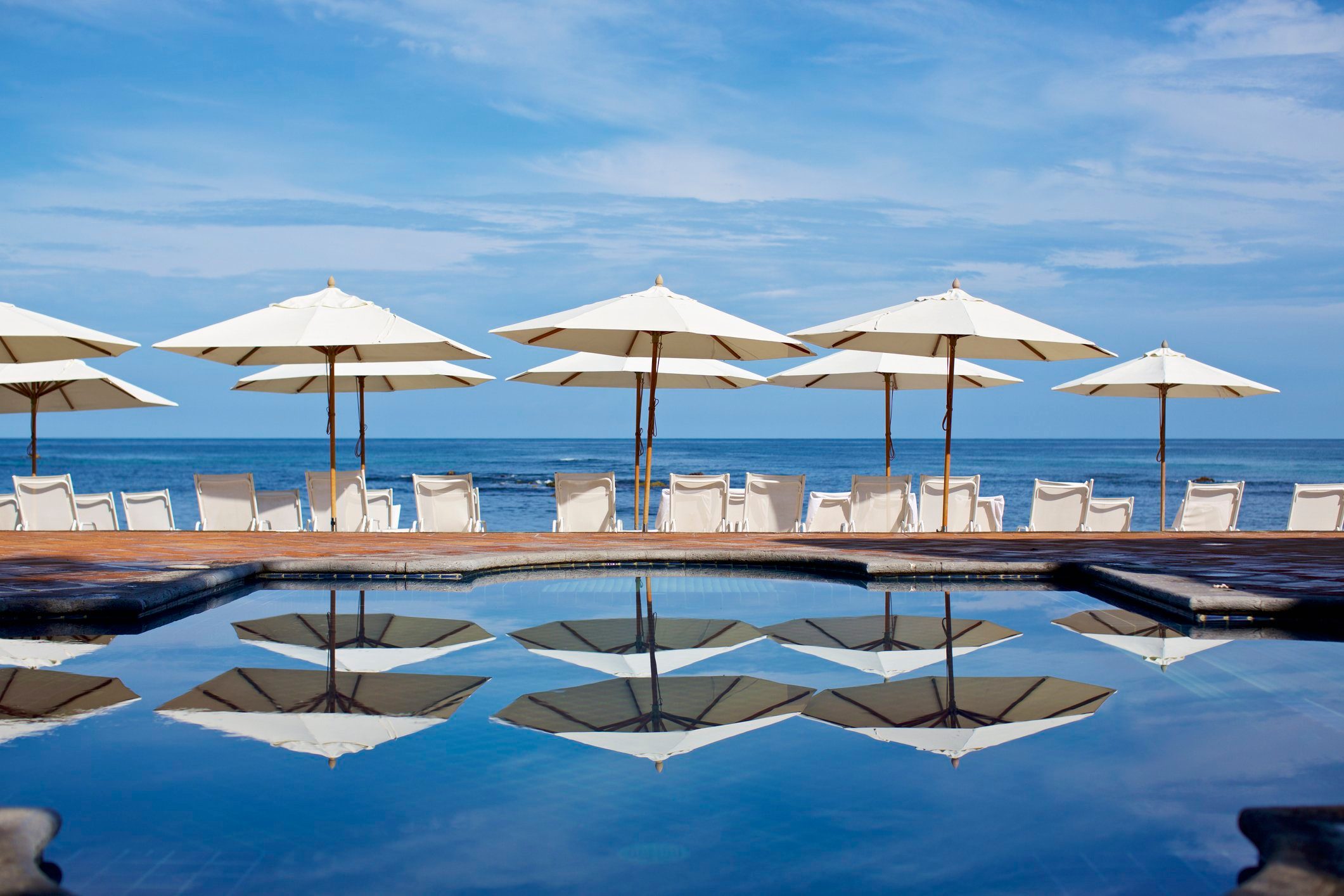 White beach umbrellas and lounge chairs at sunny ocean poolside, Punta de Mita, Nayarit, Mexico