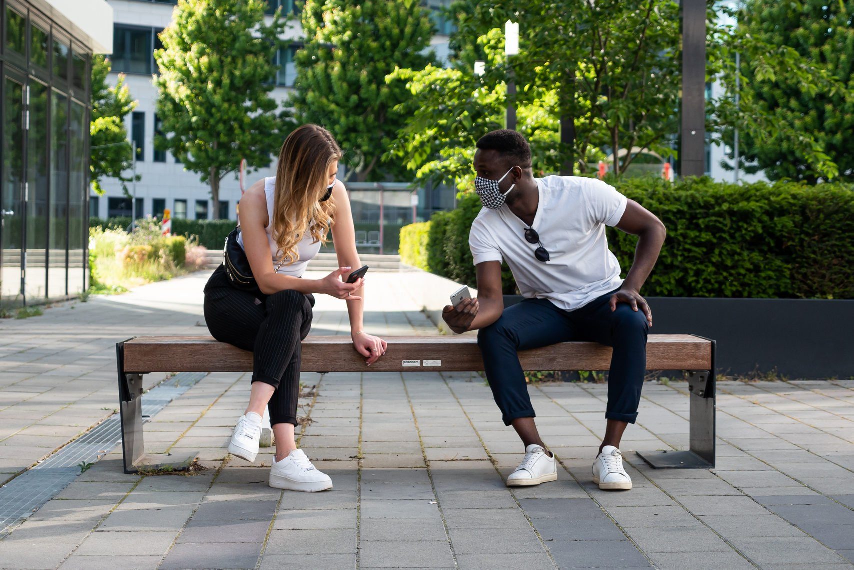 Young Man and Woman Social Distancing on Bench Using Phones