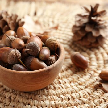 Lucky things - Acorns in wooden bowl on wicker mat