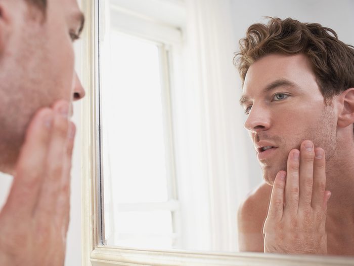 Anemia symptoms - man inspecting face in mirror